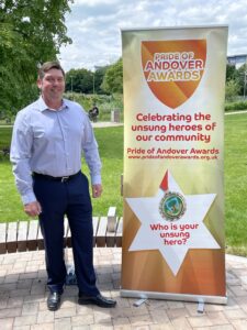 Man posing with the pride of andover unsung heroes banner